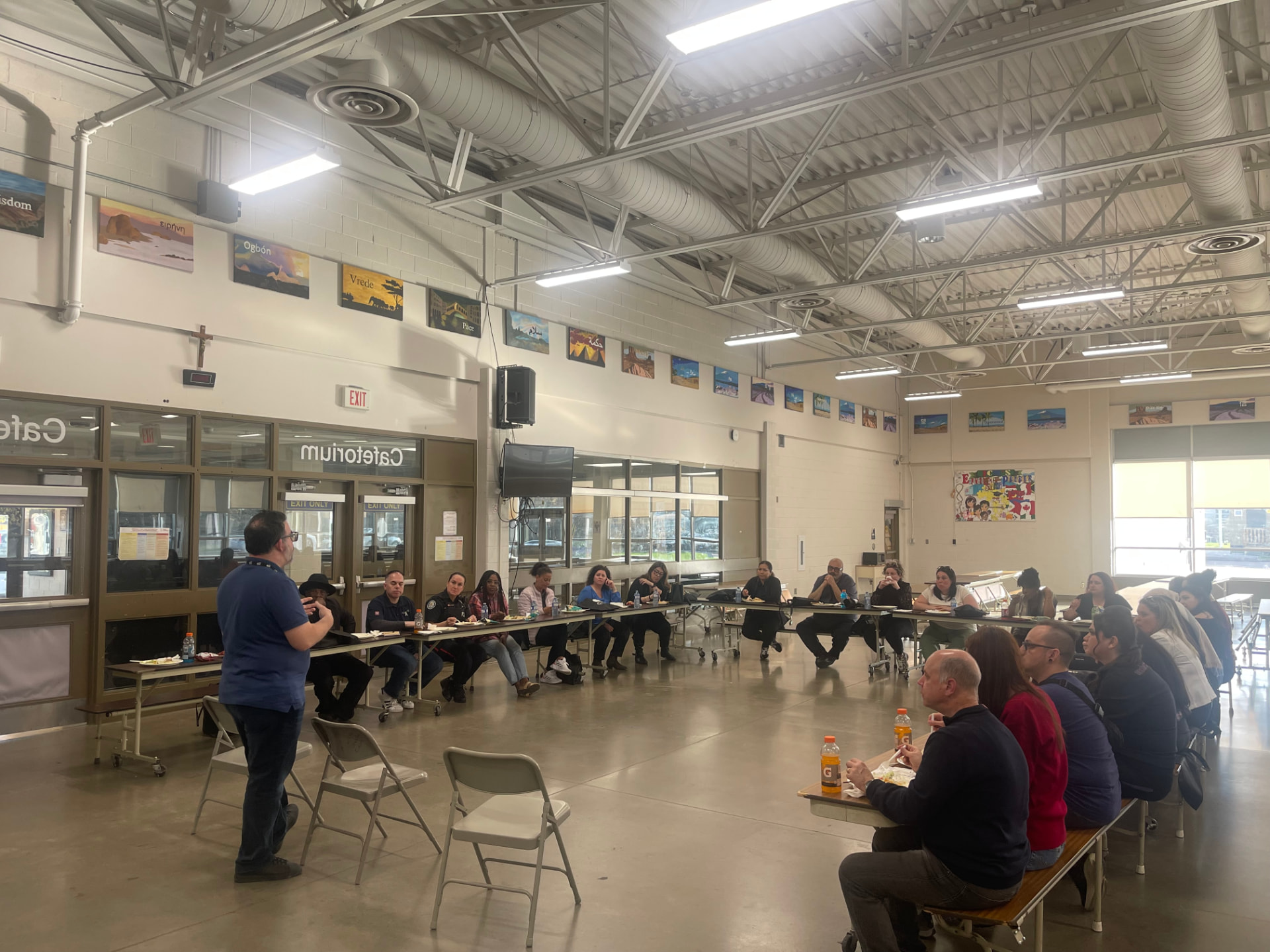 Community members seated at tables during a ward council meeting in a school cafeteria